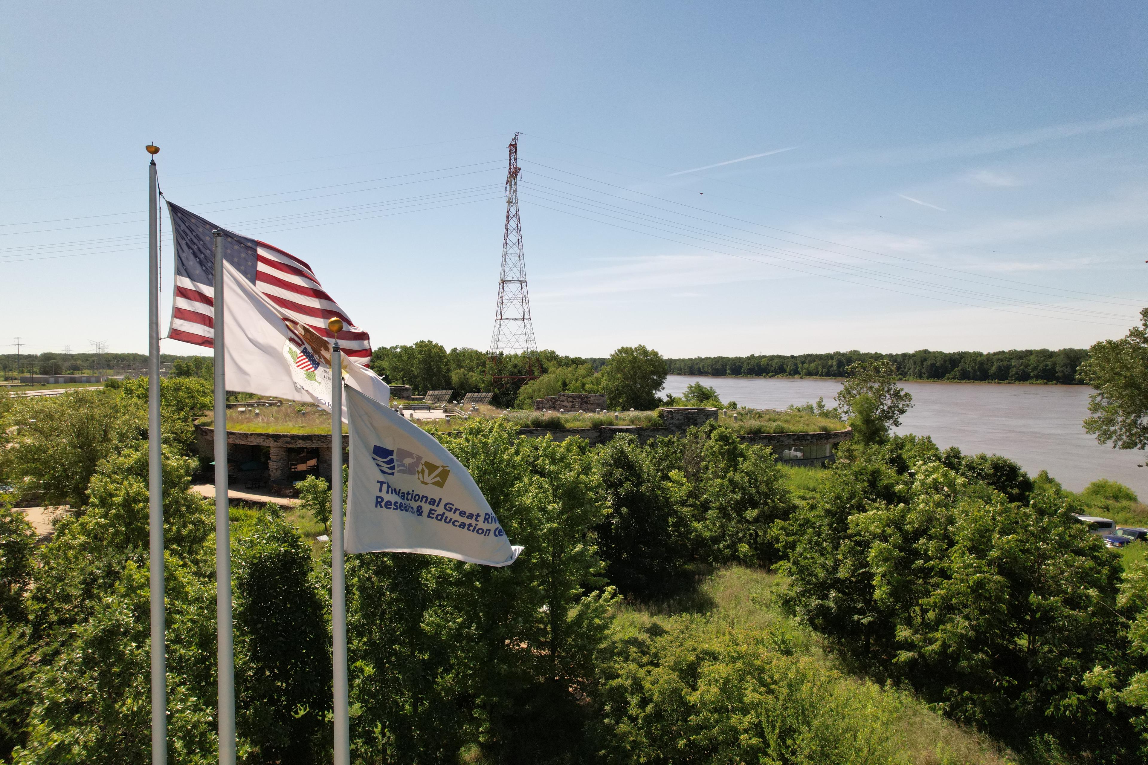 A photo of the U.S., Illinois, and NGRREC flags outside of the NGRREC field station.