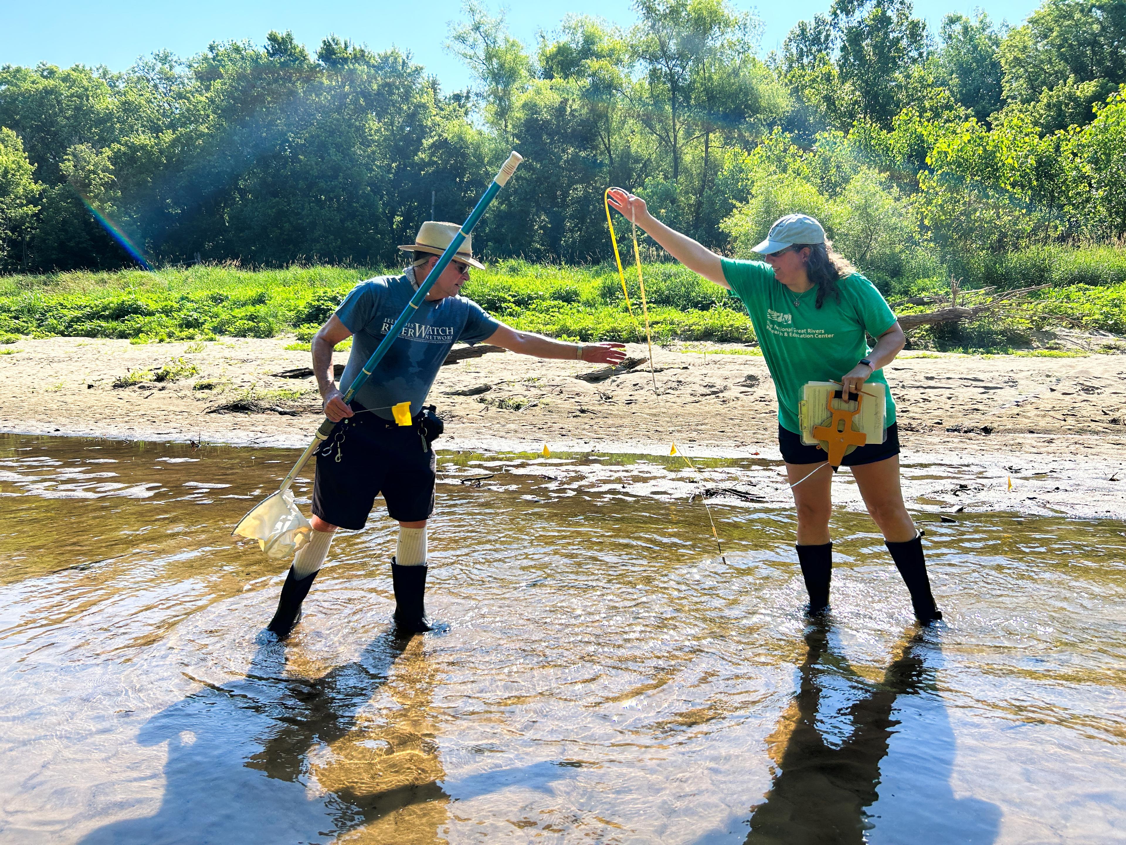 Photo of a man and a woman collecting samples in a river.
